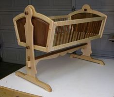 a wooden baby crib sitting on top of a white table next to a garage door