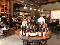 several bottles of wine are arranged on a table in a room with people sitting at tables