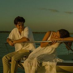 a man and woman sitting on the back of a boat next to each other,