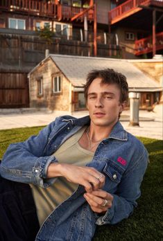 a man sitting on the grass in front of a building