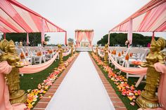 the aisle is decorated with pink and yellow flowers, gold buddha statues and white linens