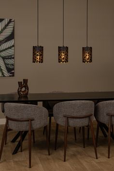 a dining room table with four chairs and three lights hanging from it's ceiling