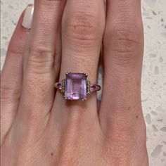 a woman's hand holding a ring with an amethorate stone in it