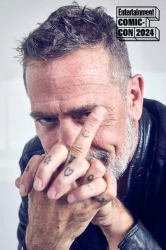 an older man with tattoos on his fingers and fingernails is looking at the camera