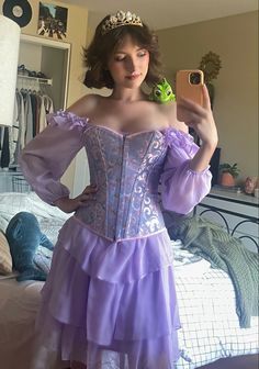 a woman in a purple dress taking a selfie with her cell phone while wearing a tiara