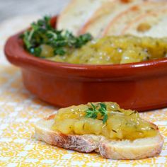 two pieces of bread sit on a yellow and white tablecloth next to a bowl of food