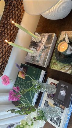 a table topped with books and flowers next to a lamp