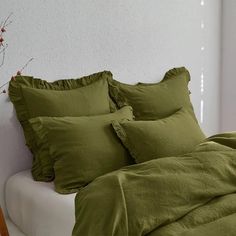 a bed with green sheets and pillows on it