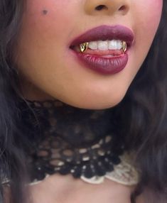 a close up of a woman with red lipstick and gold piercings on her teeth