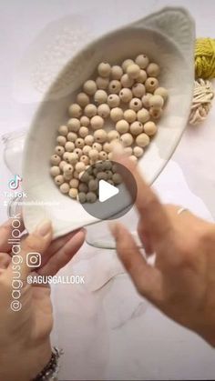 two hands holding a white bowl filled with beads