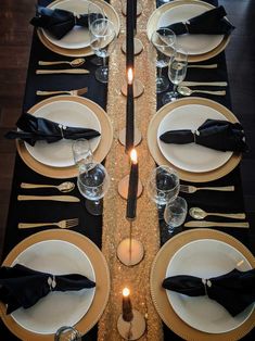 the table is set with black and gold place settings, silverware, and candles