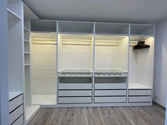 an empty walk in closet with white shelves and drawers