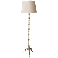 a floor lamp with a white shade on it's base and an ornate design