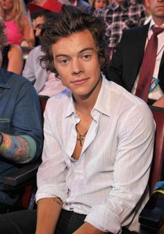 a young man sitting in front of a crowd of people wearing ties and white shirts