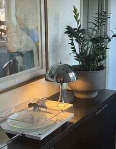 a table with a lamp on it next to a potted plant and a mirror