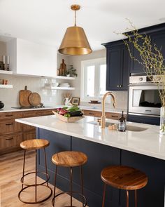 a kitchen with two stools next to an island