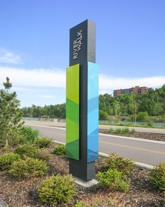 a large sign sitting on the side of a road in front of trees and bushes