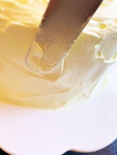 a knife is being used to cut into a white frosted cake on a plate