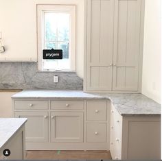 an empty kitchen with marble counter tops and white cupboards on either side of the window