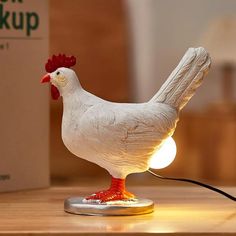 a white chicken lamp sitting on top of a wooden table next to a cardboard box