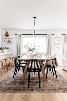 a dining room table with chairs around it and a rug on the floor in front of them