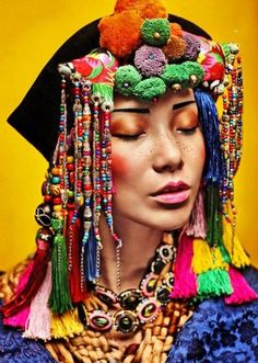 a woman with colorful hair and jewelry on her head, wearing an elaborate headdress