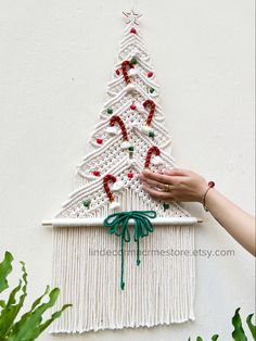 a white wall hanging with a christmas tree made out of crochet and yarn