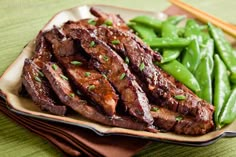 steak and green beans on a plate with chopsticks