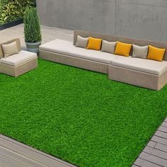 an outdoor area with grass, couches and potted plants