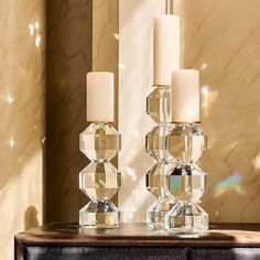 two crystal candles sitting on top of a wooden table next to a mirror and wall