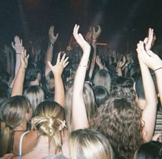 a crowd of people at a concert with their hands in the air