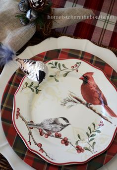 a plate with two birds on it sitting on a plaid tablecloth covered place mat