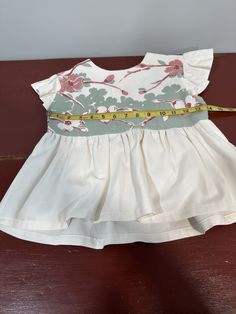 a white dress with flowers on it and a measuring tape in front of the top