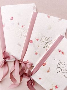 three wedding cards with pink ribbons tied around them