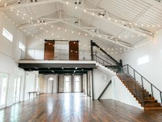 the inside of a large white building with wood floors and string lights hanging from the ceiling