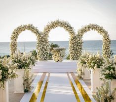 an outdoor ceremony set up with white flowers and greenery on the aisle, overlooking the ocean