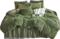 a bed covered in green fluffy blankets and pillows