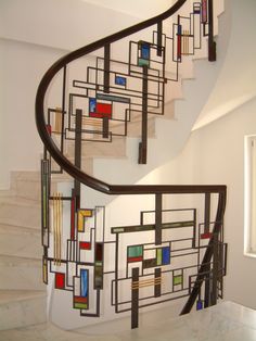 a spiral staircase in a home with white walls and marble steps, painted with multicolored squares