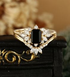 a black diamond ring sitting on top of a wooden table next to a bouquet of flowers