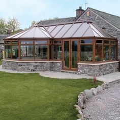 a stone building with a glass roof on the side of it and grass in front of it