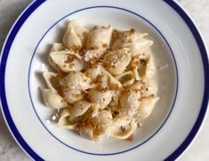 a white plate topped with pasta covered in sauce and seasoning next to a fork