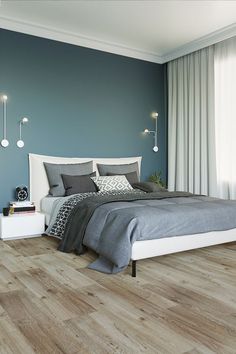 a bedroom with blue walls and wood flooring is pictured in this image, there are two lamps on either side of the bed