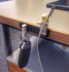 a lego keychain attached to a desk with a computer keyboard and mouse on it