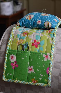 a pair of scissors sitting on top of a green and white pillow with flower designs