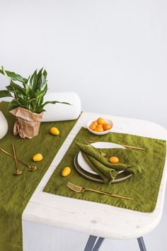 a table topped with plates and bowls filled with oranges next to a potted plant