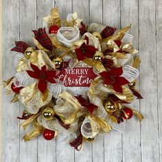 a merry christmas wreath with red and gold decorations on a white wooden background that says merry christmas