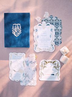 the wedding stationery is laid out on top of the bed sheet, and it's blue velvet bag