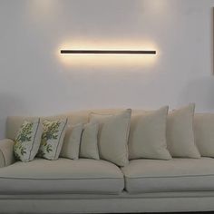 a white couch sitting under a light on the wall