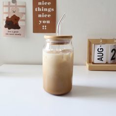 a glass jar with a straw in it sitting on a table next to a clock