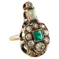 This rare and highly collectible antique ring is finely crafted in solid 14K Yellow gold (carefully tested and guaranteed). All gemstones in this ring are original to the setting. The center genuine Earth mined Colombian Emerald measures 4.5mm x 4mm (.25 carat) and this is a very clean and transparent gem of great intensity and strong brilliance. Nine old mine-cut diamonds range from VS2 to SI2 clarity and HI color for the total weight of 1.00 carat. The Opal measures 5mm x 3mm and it has splash Diamond Emerald Ring, Antique Emerald Ring, Georgian Ring, Natural Opal Ring, Natural Emerald Rings, Multi Gemstone Ring, Antique Ring, Unusual Jewelry, Colombian Emeralds